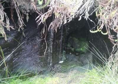 A hole containing water with more water draining into it from the heather and bog above.